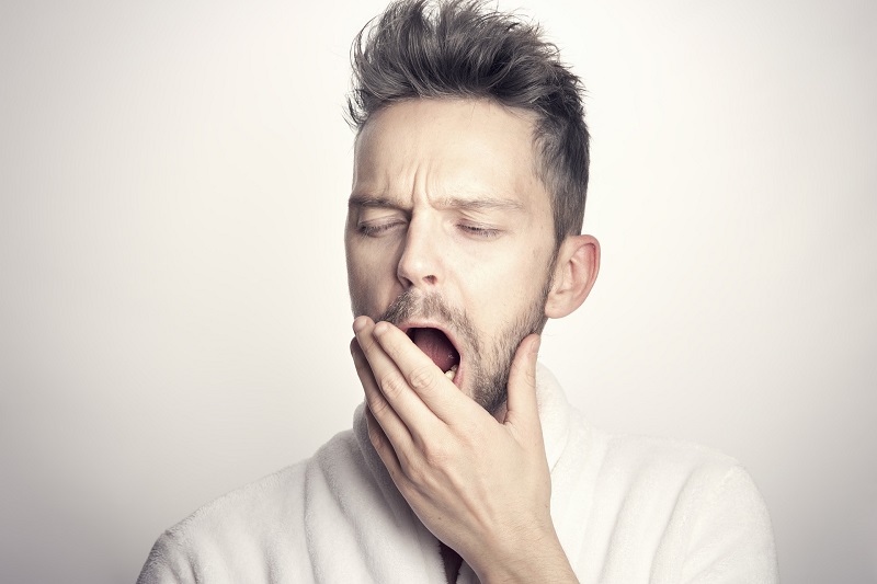 CBD Oil for Sleep Portrait of a Man Yawning with His Hand Slightly Covering His Mouth