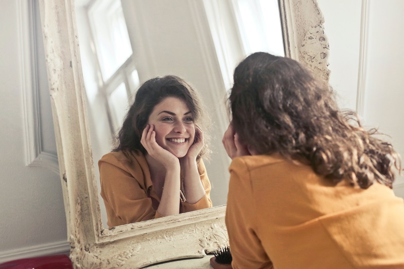 Things to Know About CBD Oil Woman Looking at Herself in a Mirror Smiling