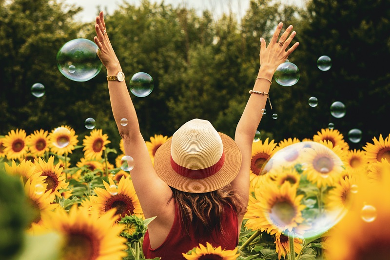 Things to Know About CBD Oil Woman Standing in a Field of Sunflowers with Bubbles Around Her and Her Arms Up in the Air