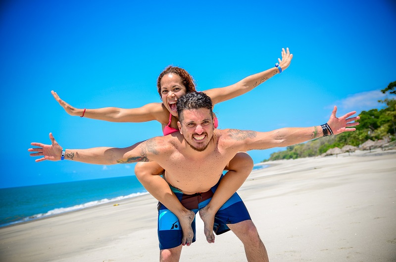 Best-Selling PlantMD Revive CBD Gummies Man Holding Up a Woman on His Back with Their Arms Stretched Out Like Wings on the Beach
