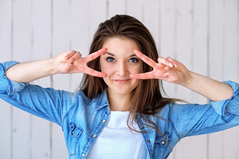 CBD Dosage Woman with Her Hands Giving Peace Signs Around Her Eyes and Smiling