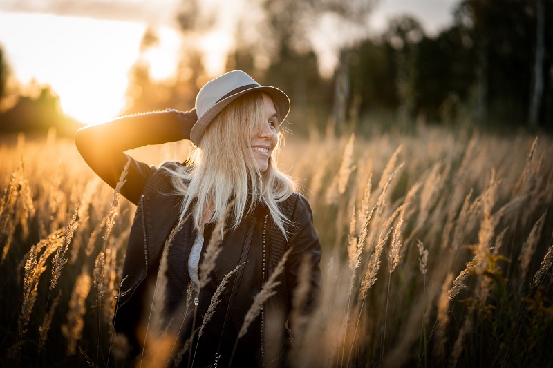 CBD Dosage Woman Holding Her Hat on Standing in a Field of Tall Grass