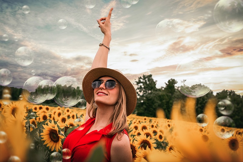 How to Use CBD for Inflammation a Woman Standing in a Field of Sunflowers with Her Arm Raised in the Air Celebrating