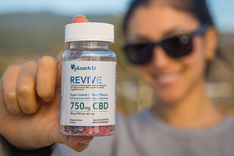 Benefits of PlantMD CBD Close Up of a Bottle of PlantMD Revive Gummies Held up by a Woman