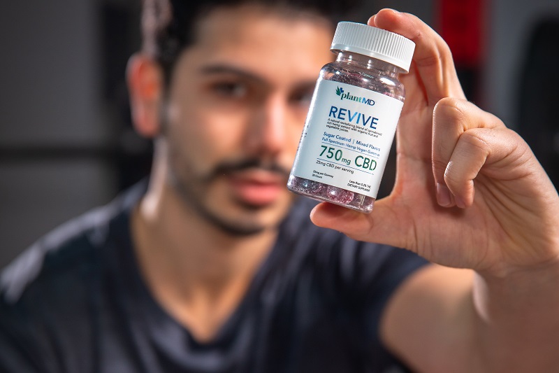 Revive Gummies Benefits Close Up of a Man Holding a Bottle of Revive Gummies