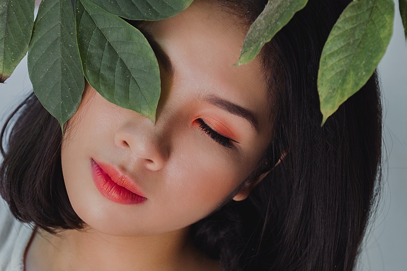 CBD Oil Benefits for the Skin Close Up of a Woman's Face with Leaves in Front of One of Her Eyes
