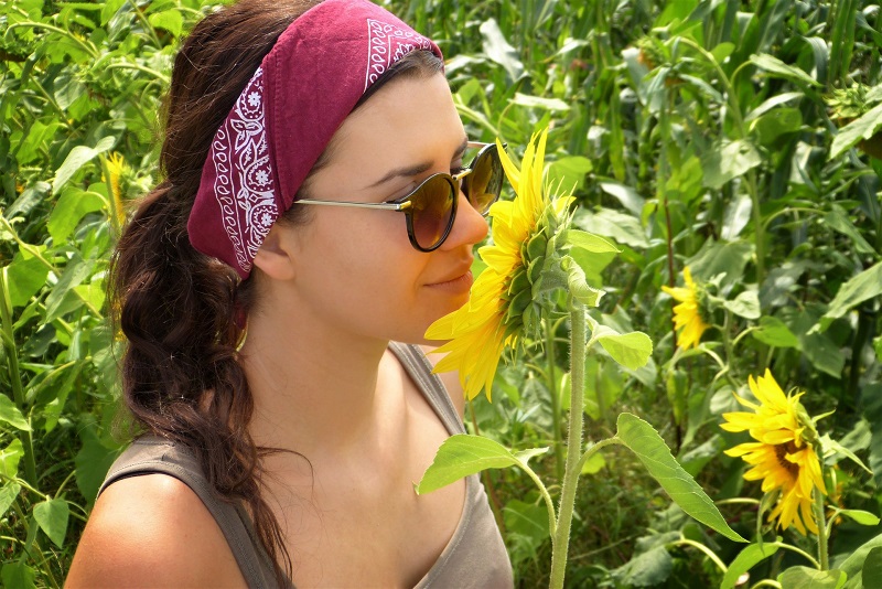 Can CBD Help with Hair Growth Woman Outside in a Field of Sunflowers Smelling One