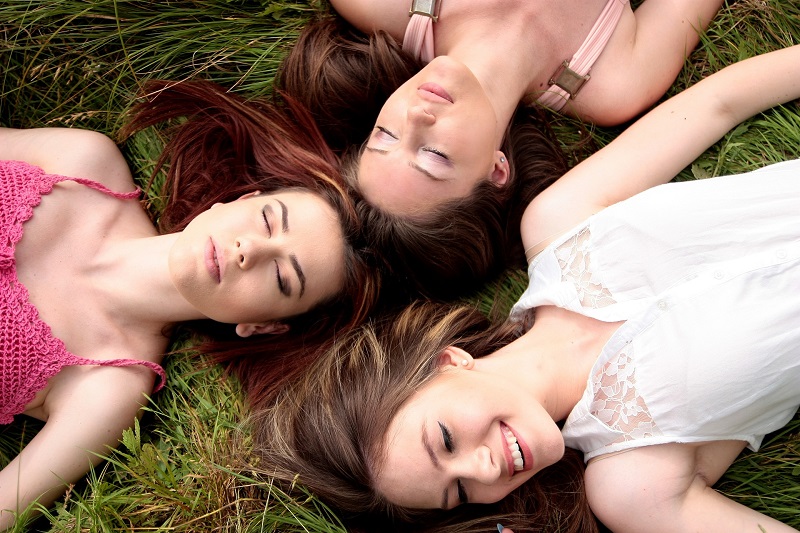 How CBD Helps with Periods a Group of Women Laying in the Grass with Their Heads Together