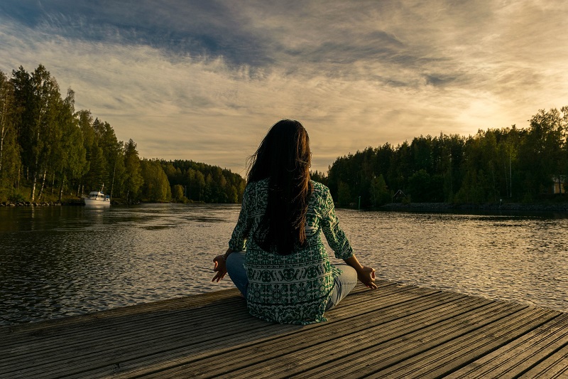 How to Use CBD for Meditation Woman Meditating on a Dock Over a Lake