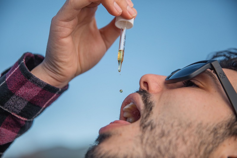 Best Time of Day to Take CBD Close Up of a Man Pouring PlantMD Revive Tincture in His Mouth from a Dropper