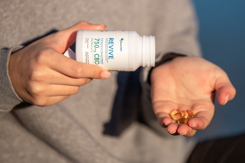 Best Time of Day to Take CBD Close Up of a Woman Pouring PlantMD Revive Capsules in Her Hand from the Bottle