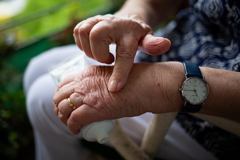 How CBD Helps with Joint Pain Close Up of an Elderly Woman Rubbing Cream on Her Hand