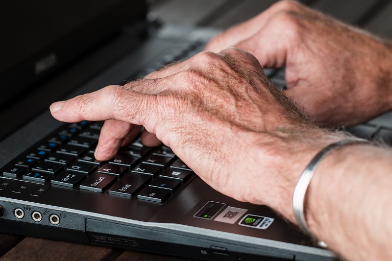 How CBD Helps with Joint Pain Close Up of an Elderly Person's Hands Typing on a Keyboard