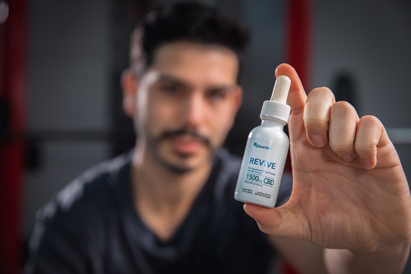 Why High-Quality Formulations Matter Most in CBD Products Man Holding Up a Bottle of PlantMD Revive Tinctures in a Gym
